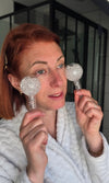 Femme en peignoir utilisant des Ice Globes transparents Method Skin sous les yeux dans une routine de soin par le froid.